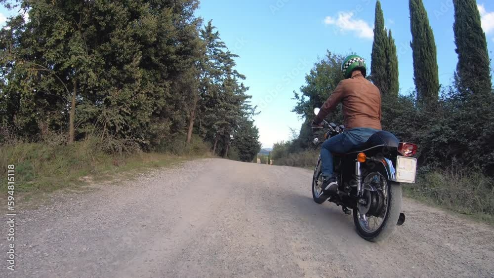 Camera car shot. Man starting and riding red motorcycle in beautiful landscape in Tuscany, Italy. Volterra. Camera car shot. Man starting and riding red motorcycle in beautiful landscape in Tuscany, Italy. Volterra.