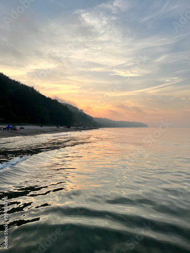 Obraz na płótnie Zachód słońca nad morzem z lasem przy plaży w salonie