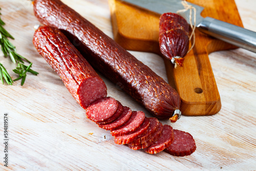 Image of russian smoked sausage cut in slices on a wooden surface, close-up .. photo