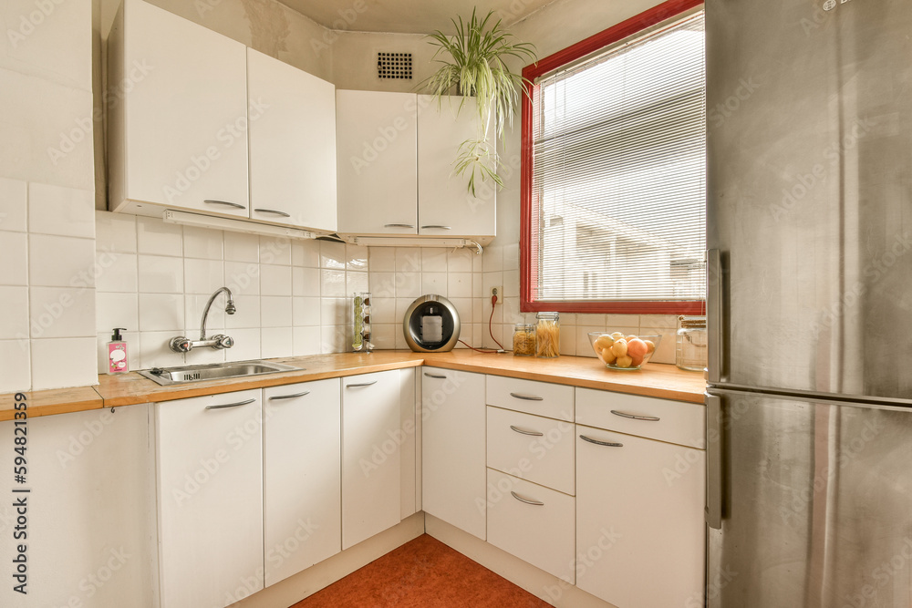 a small kitchen with white cabinets and red trim around the counters, including an orange rug on the floor a small kitchen with white cabinets and red trim around the counters, including an orange rug on the floor
