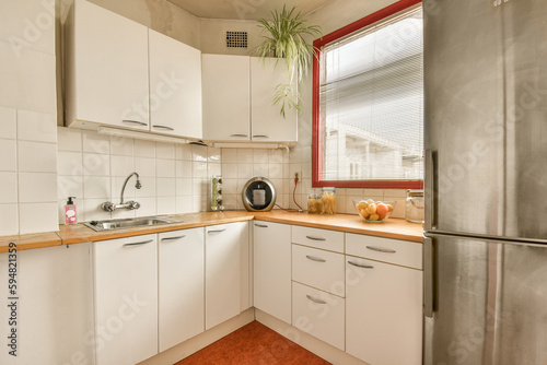 a small kitchen with white cabinets and red trim around the counters, including an orange rug on the floor