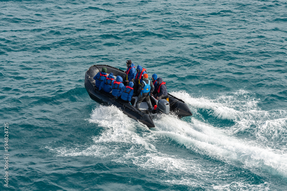 Obraz premium Tourists and Expedition Leader on a Pontoon Boat Riding Through the Waves on a Polar Excursion in Antarctica