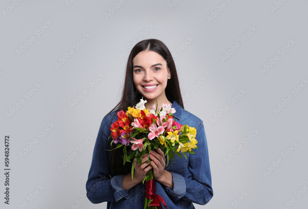 Happy young woman with beautiful bouquet on light grey background Happy young woman with beautiful bouquet on light grey background
