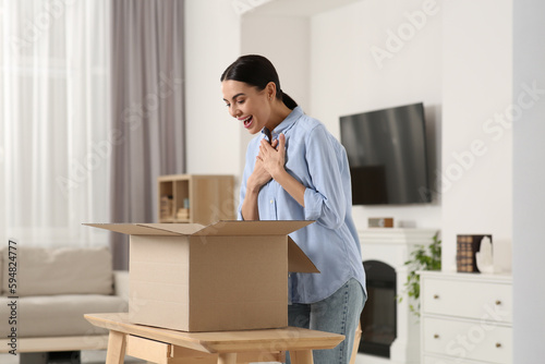Emotional young woman with opened parcel at home. Internet shopping © New Africa