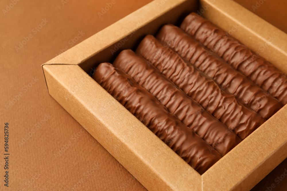 Sweet tasty chocolate bars in box on brown background, closeup Sweet tasty chocolate bars in box on brown background, closeup