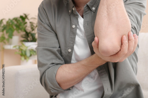Photography Man suffering from pain in his elbow at home, closeup