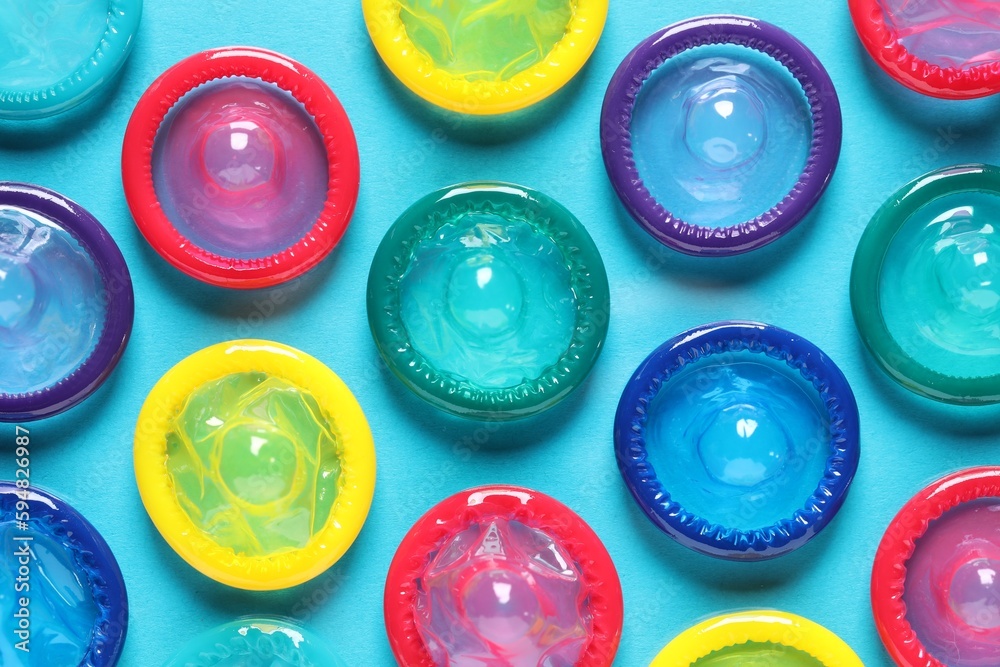 Colorful condoms on light blue background, flat lay Colorful condoms on light blue background, flat lay