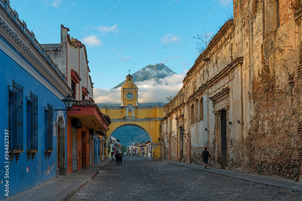 Antigua city and Santa Catalina arch with unrecognizable people before sunrise, Guatemala.