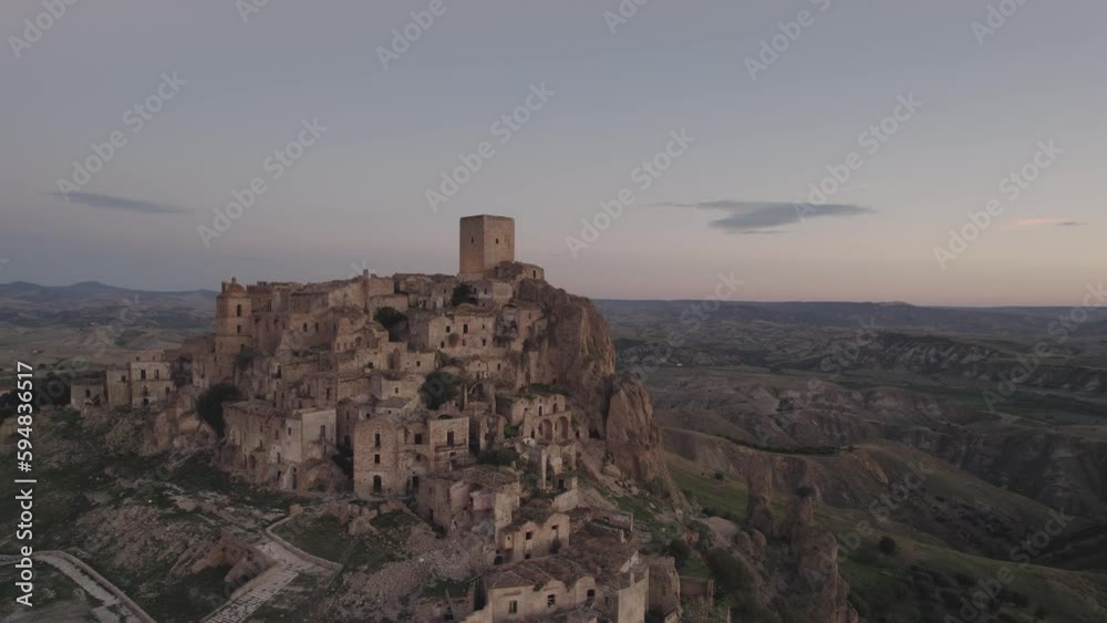 Drone flying in large circulair motion around the ruins of Craco on a hill with the sunrise in the background in 4k Drone flying in large circulair motion around the ruins of Craco on a hill with the sunrise in the background in 4k