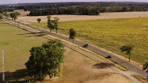 A drone flight panning across a busy country road, overlooking fields and a forest, located in Brandenburg Germany.