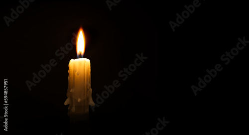Burning wax candle against a black background