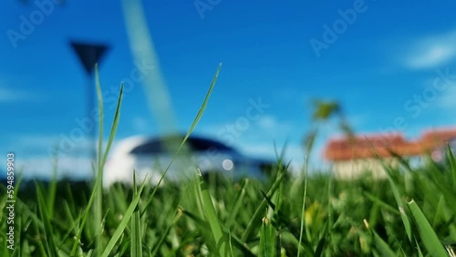 Autos desenfadados pasando en una calle con un día soleado y el césped enfocado en primer plano. photo