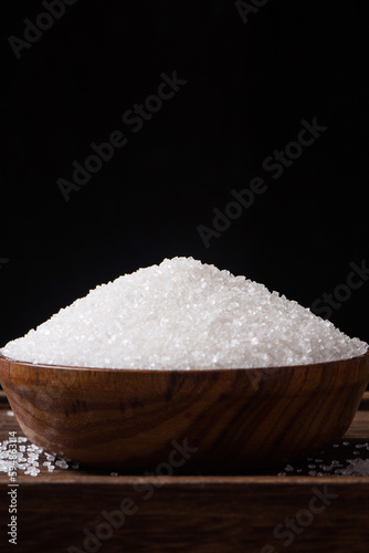Bowls are filled with sugar on a wooden background