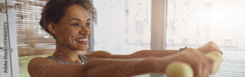 Smiling woman with dumbbells doing exercising at home and working on arms strength