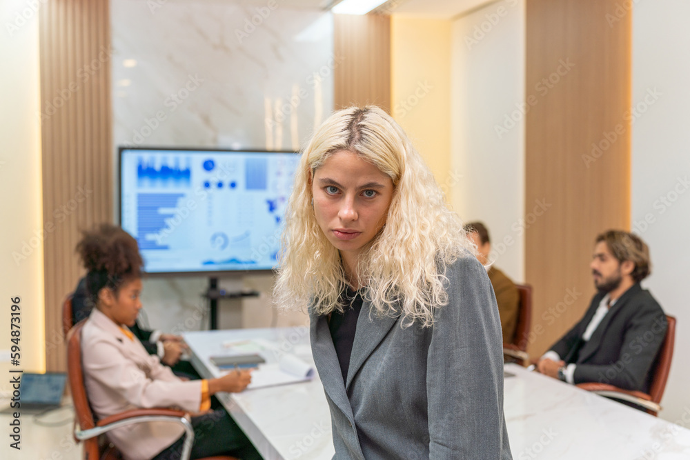 Serious angry look of a blonde businesswoman manager in a meeting room with her team of staffs because of bad sales report Serious angry look of a blonde businesswoman manager in a meeting room with her team of staffs because of bad sales report