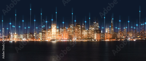 City, night and skyline by water with tech, network or light overlay for connection, iot or mockup space. Dark metro, cbd and skyscraper by ocean for development, infrastructure or futuristic mock up