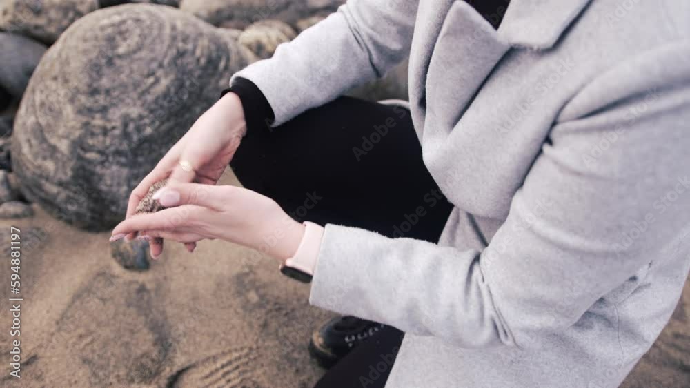 Static shot of a woman brushing sand off a rock then putting the stone in her pocket. Filmed at Dail Beag beach on the Isle of Lewis, part of the Outer Hebrides of Scotland. Static shot of a woman brushing sand off a rock then putting the stone in her pocket. Filmed at Dail Beag beach on the Isle of Lewis, part of the Outer Hebrides of Scotland.