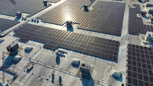 Aerial view of blue photovoltaic solar panels mounted on industrial building roof for producing green ecological electricity. Production of sustainable energy concept
