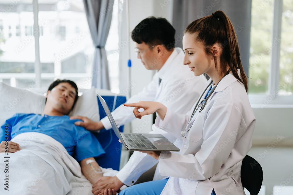 Two doctors talking to a patient lying in his bed with receiving saline solution in hospital . Two doctors talking to a patient lying in his bed with receiving saline solution in hospital .