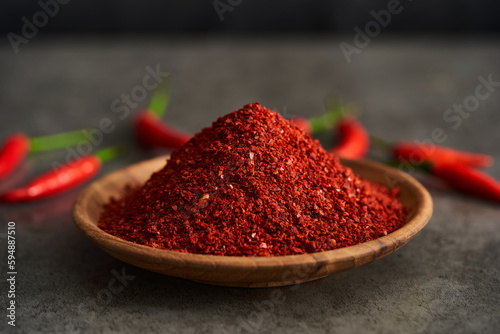 red chili pepper flake or ground powder coarse in wood bowl on gray stone food background. red chili pepper flake or ground powder coarse food. red chili pepper flake or ground powder coarse