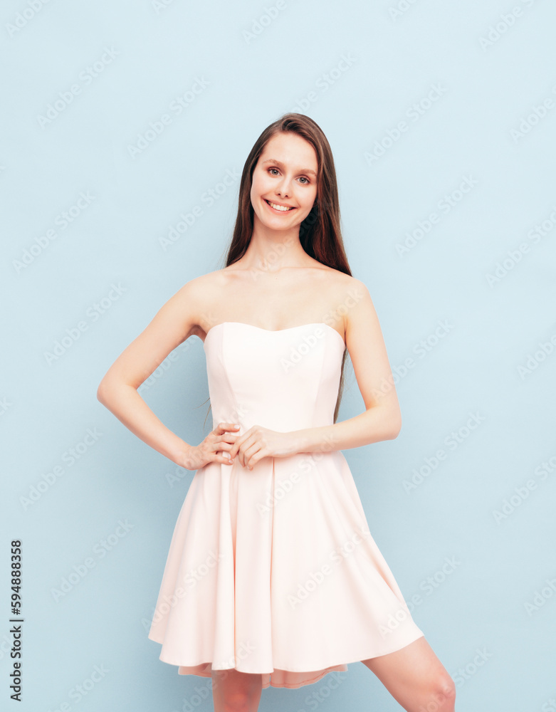 Portrait of young winsome woman in romantic attire pretty smiling on blue background. Slim female in pure pink dress posing in studio. Cheerful model. Isolated. Long hair Portrait of young winsome woman in romantic attire pretty smiling on blue background. Slim female in pure pink dress posing in studio. Cheerful model. Isolated. Long hair