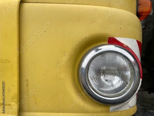 Detail of the round headlight of a yellow IFA W50 truck manufactured in the German Democratic Republic. High quality photo
