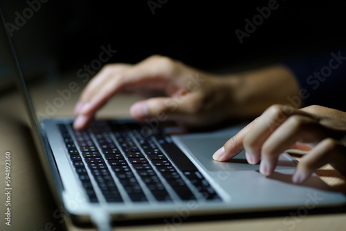 Close up of a man's hands on keyboard of lap top in the dark room, people working at home, modern white notebook. Internet, work, technology concept.