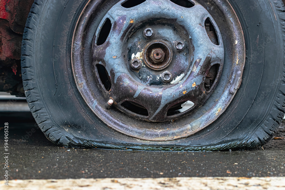 flat car tire close up, punctured wheel. A punctured tire while traveling by car. Replacing a punctured wheel.