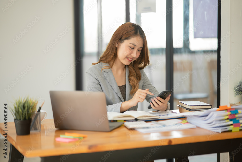 Asian businesswoman reading graphs and talking on phone with customers in office Asian businesswoman reading graphs and talking on phone with customers in office