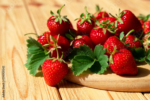 Delicious juicy strawberries on wooden board on wooden background. Farm strawberry harvest. Healthy eating, raw diet and detox food concept. Natural source of vitamins and antioxidants.