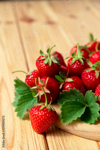 Delicious juicy strawberries on wooden board on wooden background. Farm strawberry harvest. Healthy eating, raw diet and detox food concept. Natural source of vitamins and antioxidants.