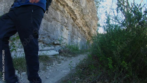 Man in sportswear hiking on a trail at the bottom of a beautiful cliff