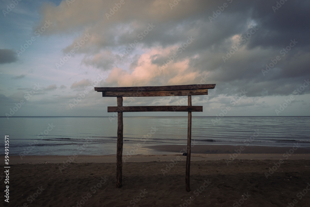 Wooden Japanese torii gate along the beach at sunrise.