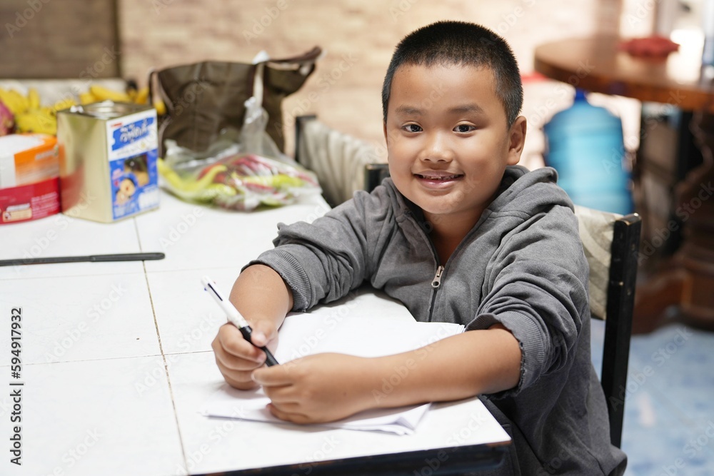 boy holding a pen sitting at the desk