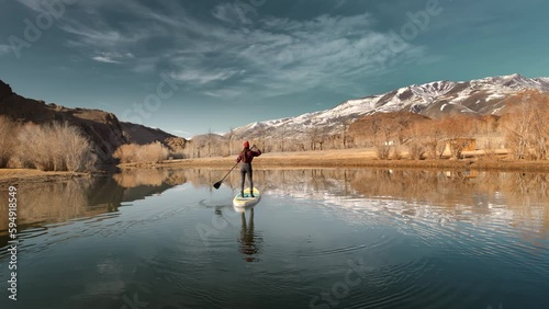 Slim sporty girl is walking on stand up paddle sup board at calm mountain in mountains river photo