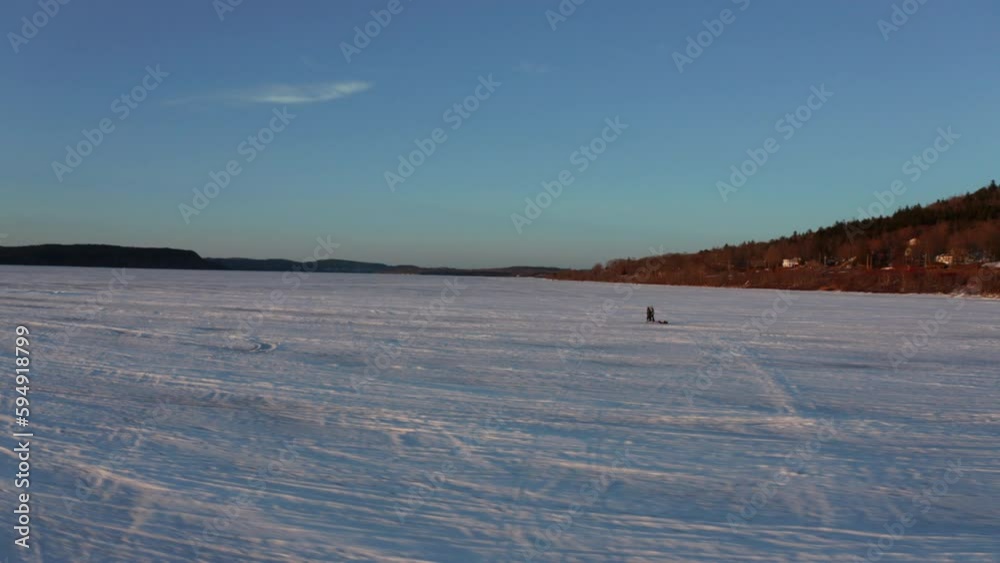 Scenic aerial view of people walking across a frozen, snow covered lake at sunset. Scenic aerial view of people walking across a frozen, snow covered lake at sunset.