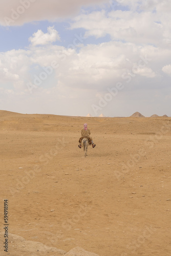 man riding a donkey in the distance in the desert of Saqqara, alone in the vastness of the desert