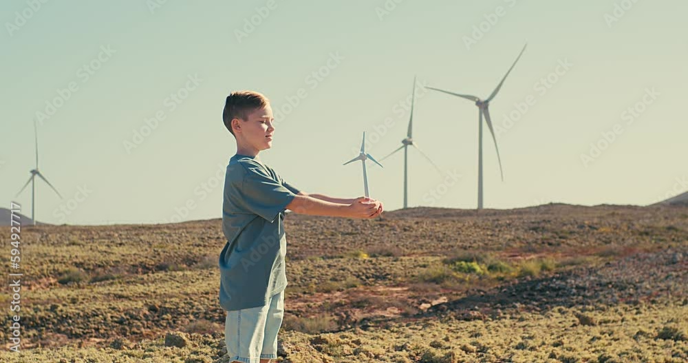 Happy child on looking at wind energy turbine sat wind farm site, alternative energy, wind farm and happy time with your family, Earth Day	