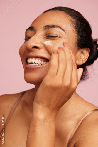 Konstfotografi Smiling woman applying moisturizer cream on face