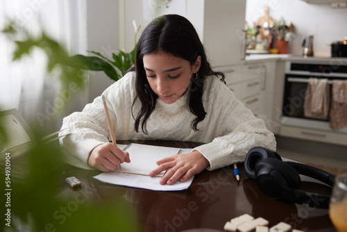 Girl doing homework at dining table photo