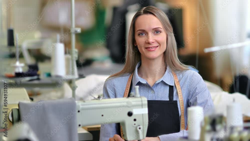 Woman seamstress dressmaker smiling posing tailoring atelier workplace electric sewing machine Woman seamstress dressmaker smiling posing tailoring atelier workplace electric sewing machine