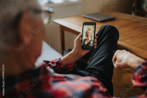 Senior man talking to woman via video call photo