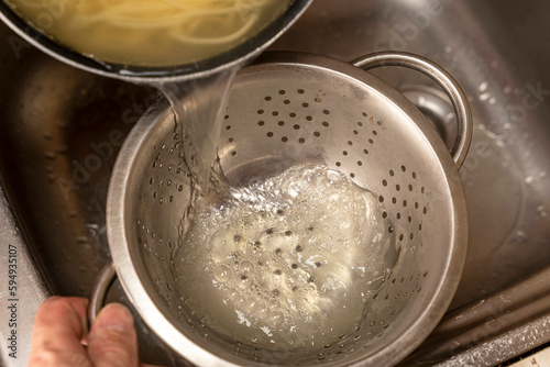 Colander with fresh cooked spaghetti in kitchen