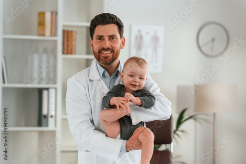 Holding boy in hands. Doctor with little baby is working in the cabinet © standret
