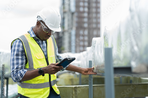 Photography Male engineer worker working with digital tablet inspecting quality ventilation, air conditioning at rooftop of building