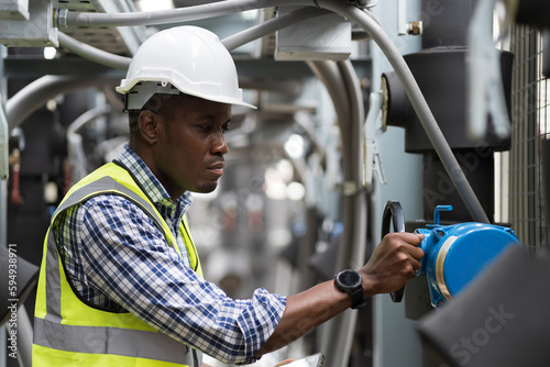 Male plumber engineer inspecting quality of work at sewer pipes area at construction site. African American male engineer worker check or maintenance sewer pipe network system at rooftop of building