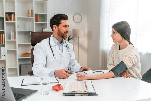 Blood pressure measurement. With woman. Doctor in formal clothes is working in the cabinet