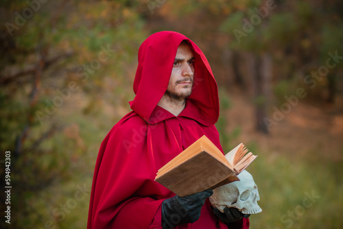 A sorcerer in red clothes with a skull and a book in his hands reads a spell. Medieval monk reads a prayer.