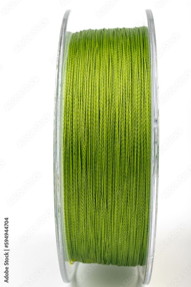Braided green line for fishing on a transparent coil, isolate, close-up