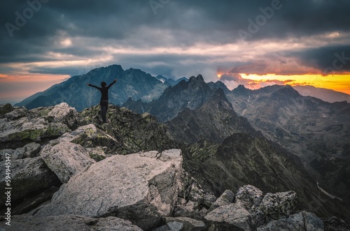 Beautiful dark landscape with the theme of freedom in the rocky mountains. Girl on top of a mountain in a gesture of freedom and victory in the Slovak High Tatras.
